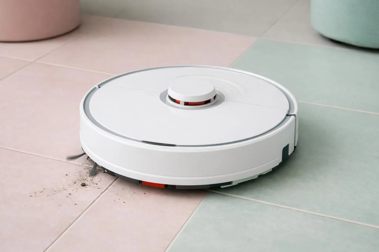 A white robotic vacuum cleaner on a tiled floor.